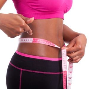 woman with measuring tape around waist show weight loss